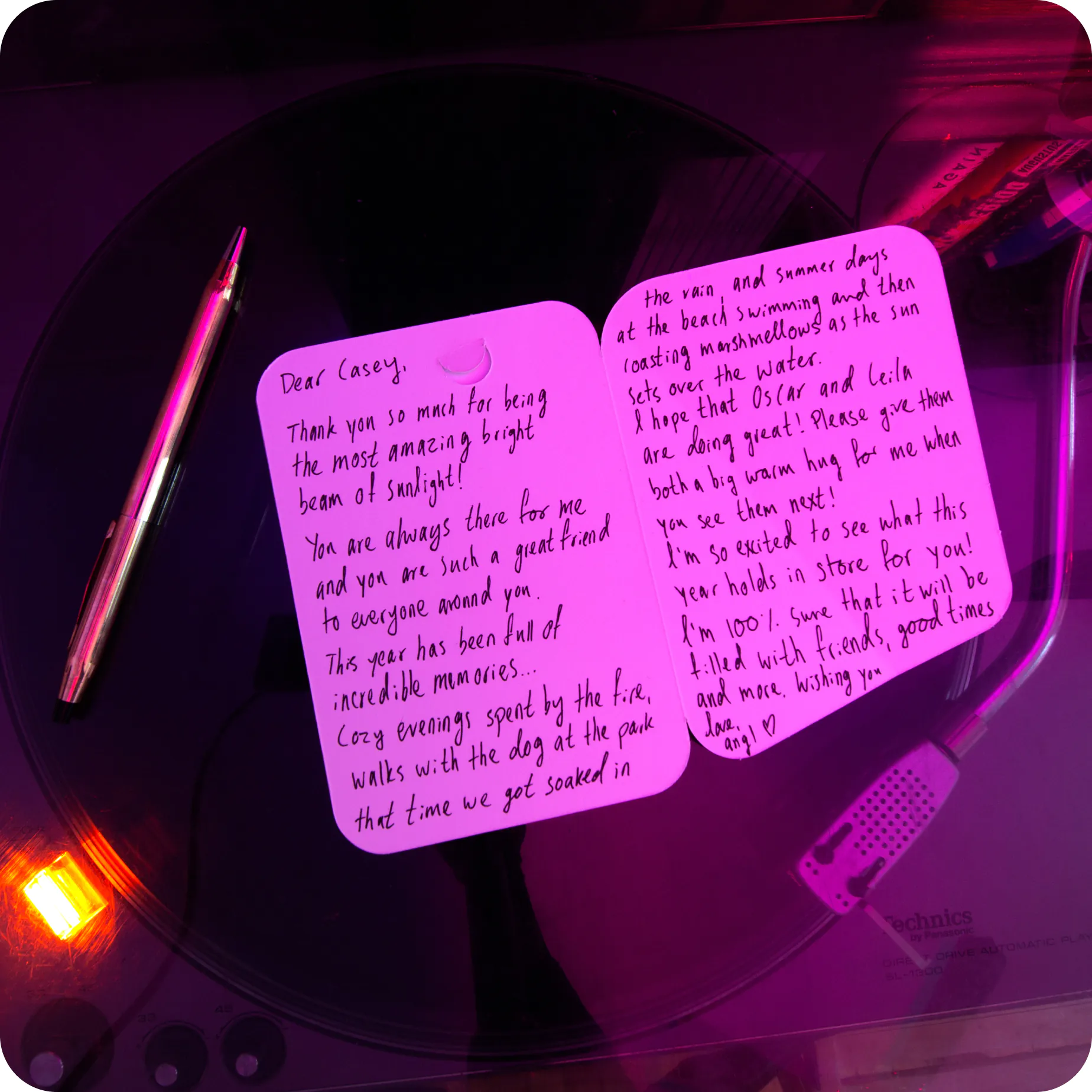 A handwritten message inside a Pop-up Frame card, resting on a record player in pink light